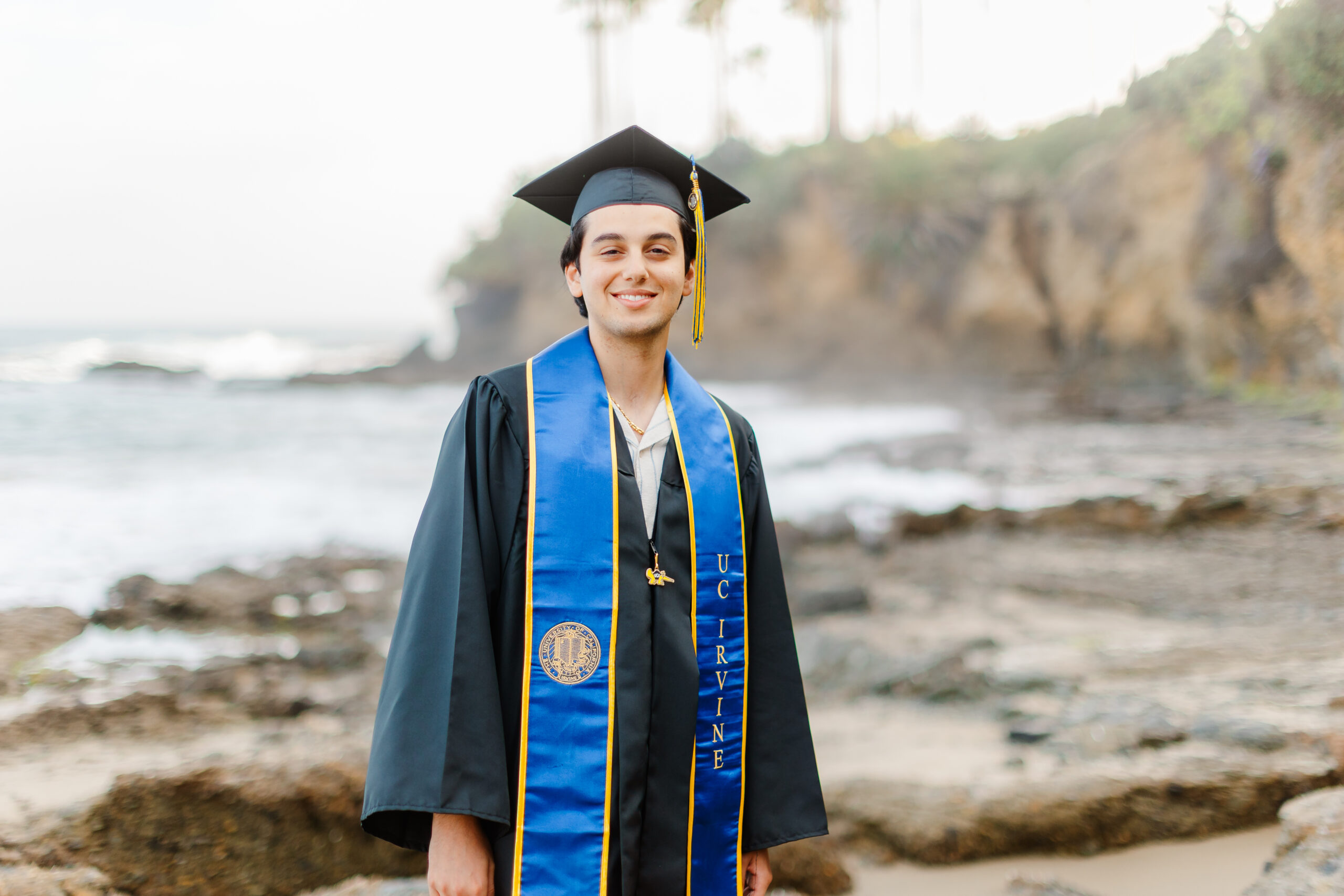 UC Irvine graduate Cyrus in cap and gown at Laguna Beach